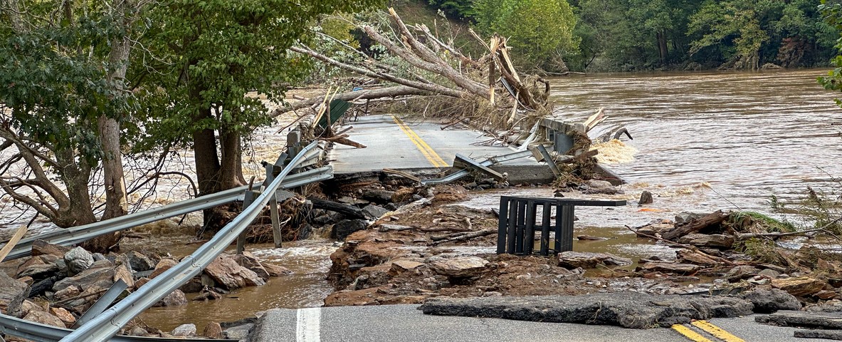 A road is missing a segment due to a flooded river.